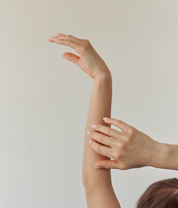 Woman in a peaceful yoga pose against a dark background with ruby light.